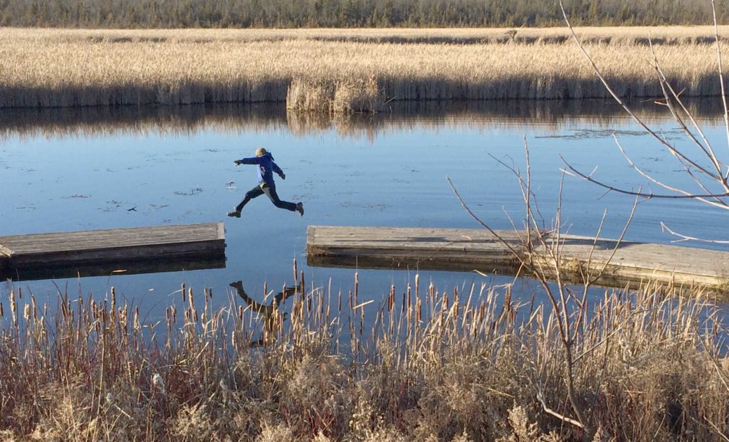Trail hiker jumping across water